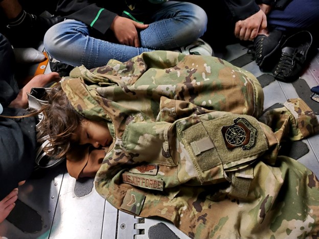 An Afghan child sleeps on the cargo floor of a U.S. Air Force C-17 Globemaster III during an evacuation flight from Kabul, Afghanistan, Aug. 18, 2021. Operating a fleet of Air National Guard, Air Force Reserve and Active Duty C-17s, Air Mobility Command, in support of the Department of Defense, moved forces into theater to facilitate the safe departure and relocation of U.S. citizens, Special Immigration Visa recipients, and vulnerable Afghan populations from Afghanistan. (U.S. Air Force courtesy photo)