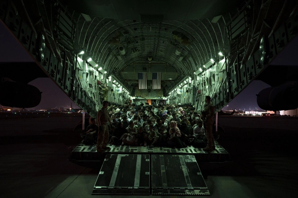 A U.S. Air Force aircrew, assigned to the 816th Expeditionary Airlift Squadron, assists qualified evacuees aboard a U.S. Air Force C-17 Globemaster III aircraft in support of the Afghanistan evacuation at Hamid Karzai International Airport, Afghanistan, Aug. 21, 2021. The Department of Defense is committed to supporting the U.S. State Department in the departure of U.S. and allied civilian personnel from Afghanistan and to evacuate Afghan allies to safety.